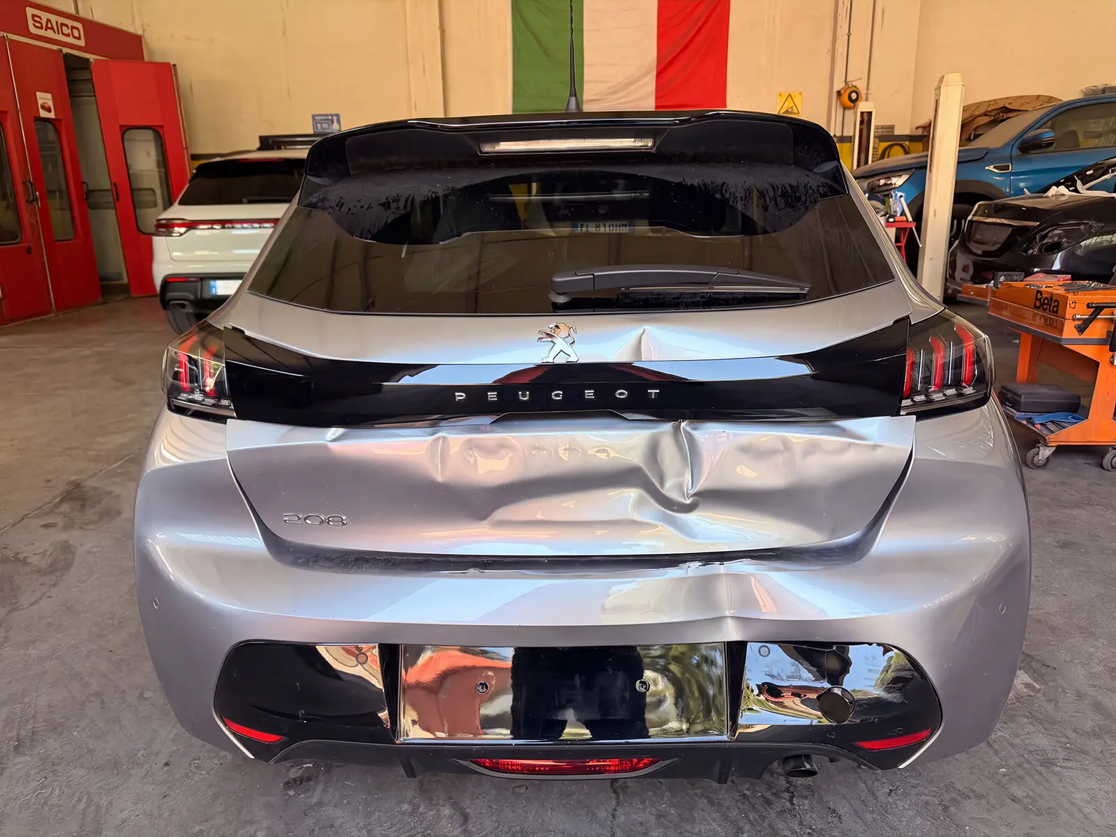 Peugeot 208 grigia con portellone posteriore ammaccato, in carrozzeria per la riparazione