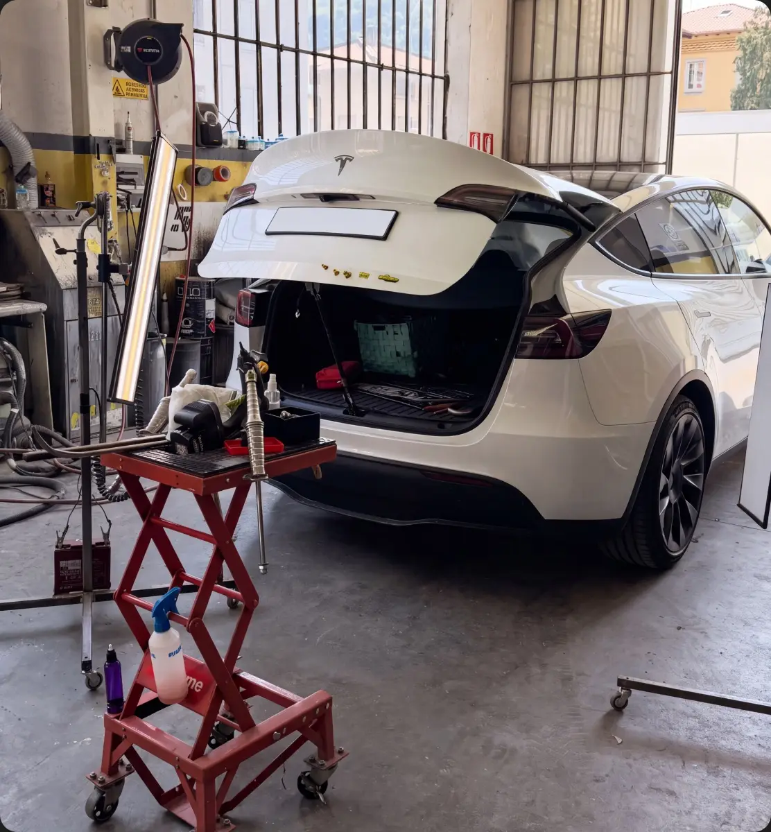 Vettura bianca sollevata in officina con portellone posteriore aperto